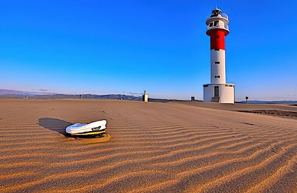 a captain 's hat is laying in the sand near a lighthouse