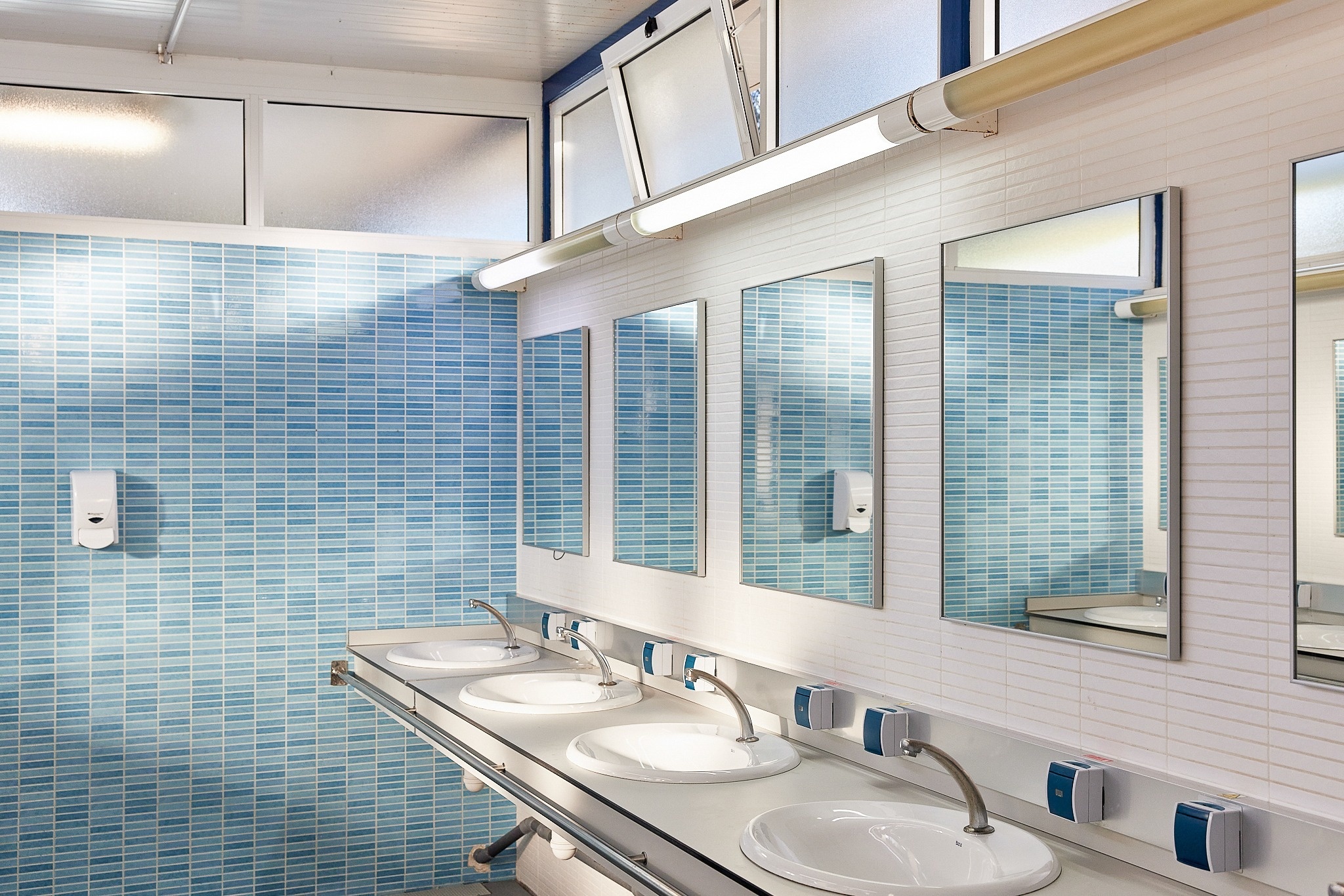 een badkamer met blauwe tegels en spiegels