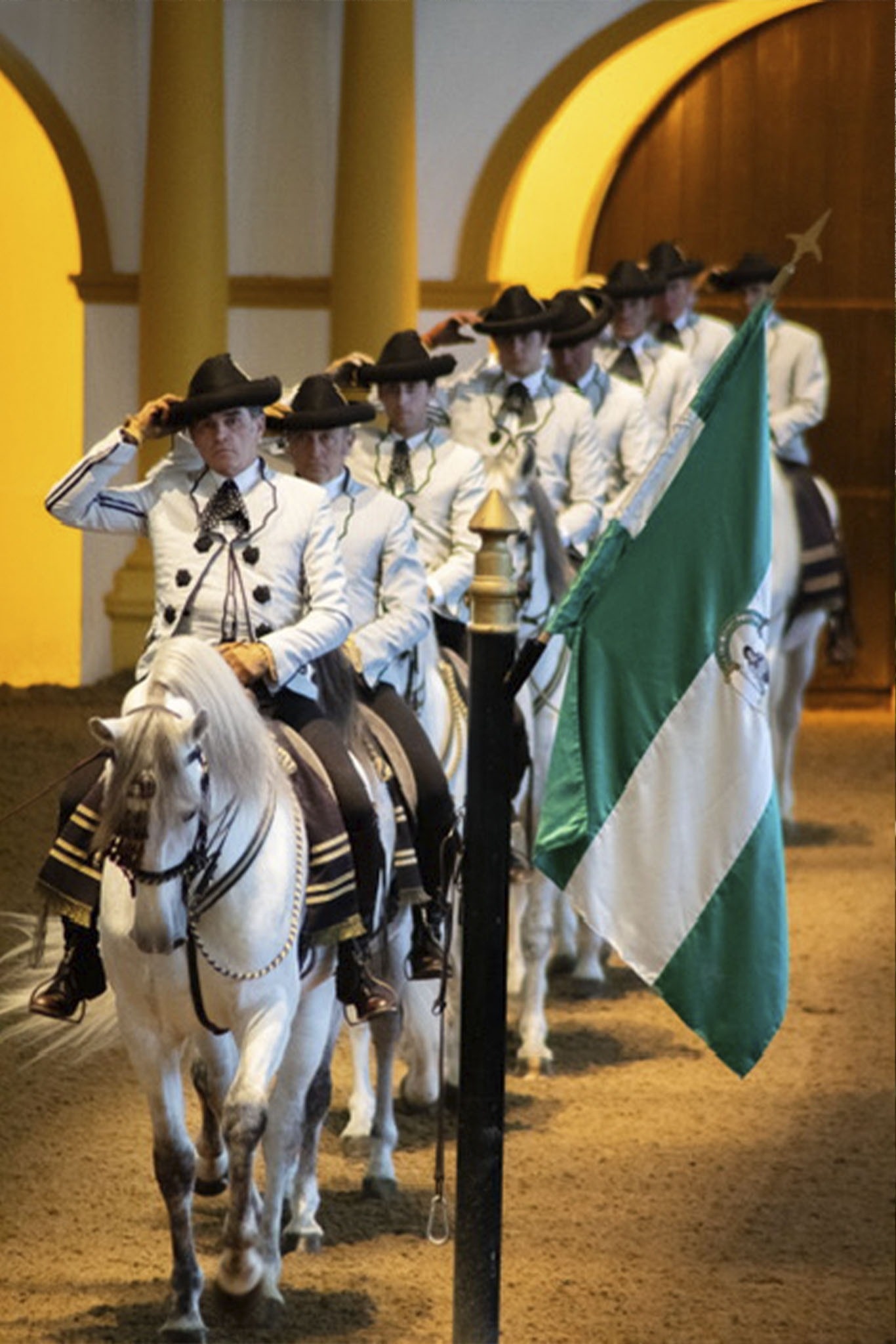 un grup d' hombres a caballo llevan una bandera verde y blanca