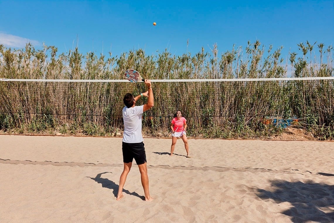 a man and a woman are playing tennis on the beach