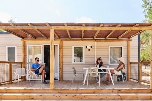 ein Mann in einem blauen shirt steht vor einem mobilen Haus auf einer Veranda .