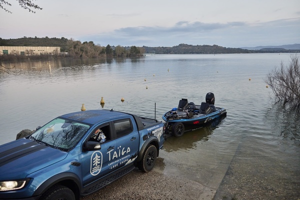 ein blauer taigo-Truck steht neben einem Boot im Wasser