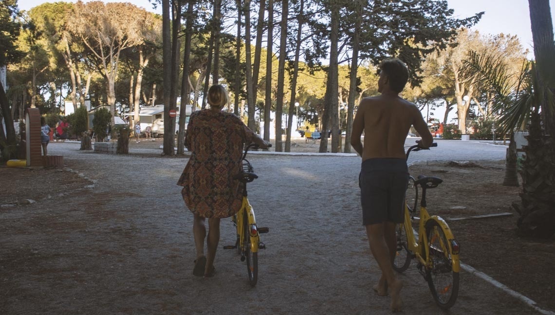 een man en een vrouw lopen met hun fietsen op een onverharde weg