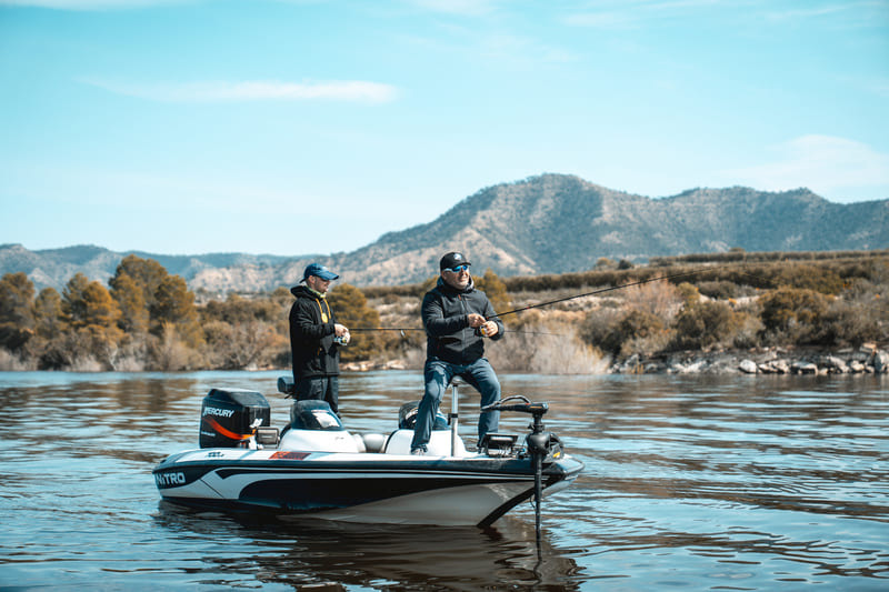 Pesca en lago con dos personas en bote Taiga, paisaje sereno.