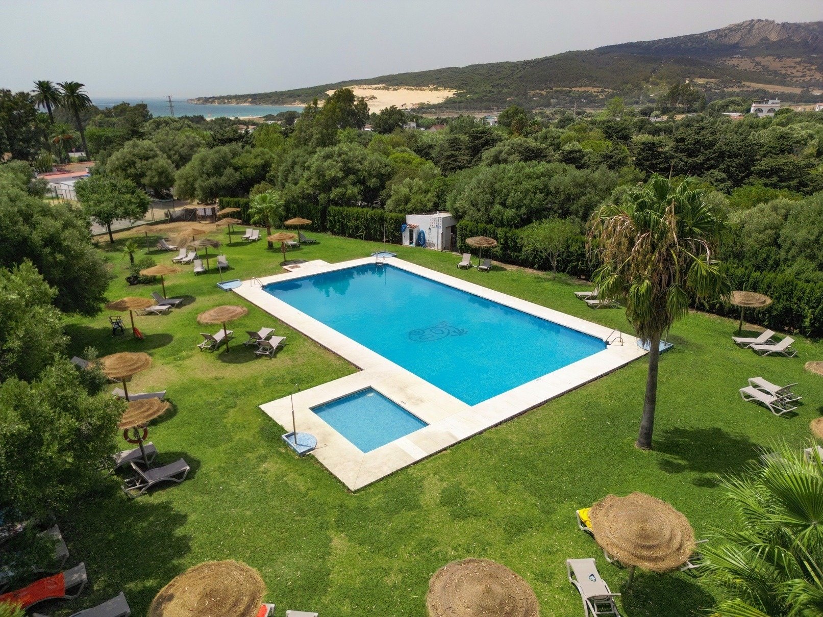 an aerial view of a large swimming pool surrounded by chairs and umbrellas