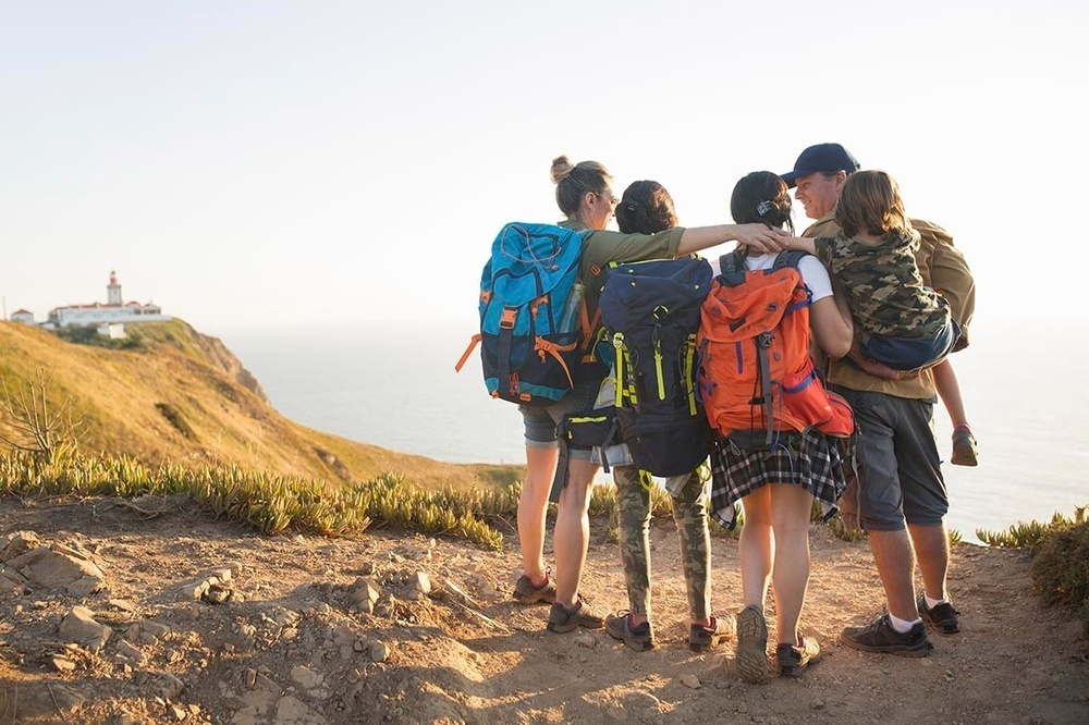un grup de persones amb mochilas mirant el mar