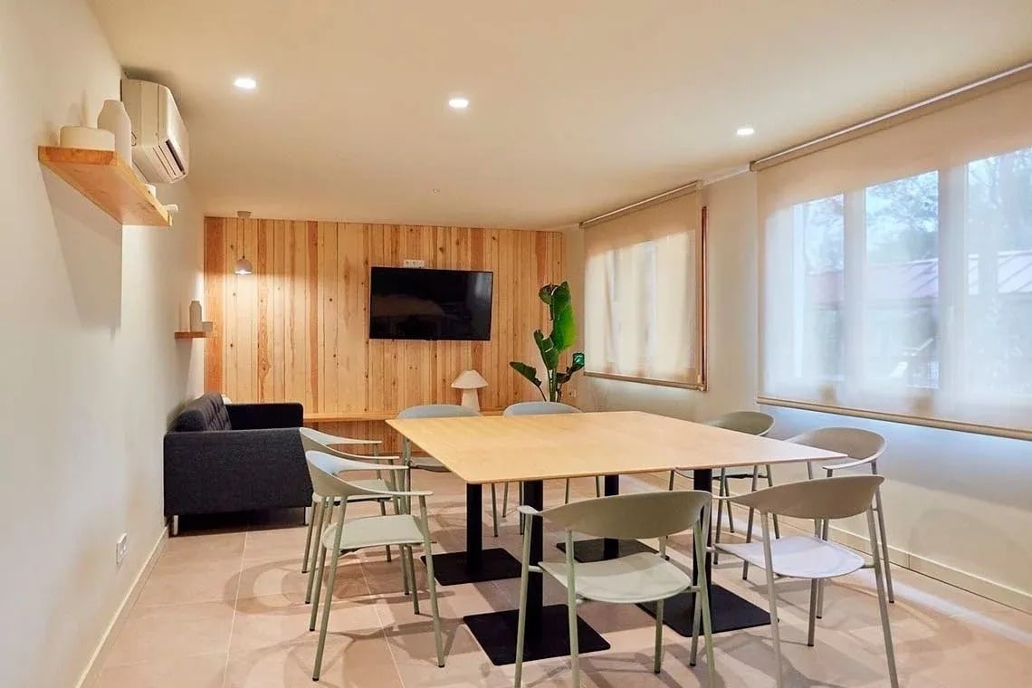 una habitación con mesas y sillas y una televisión en la pared