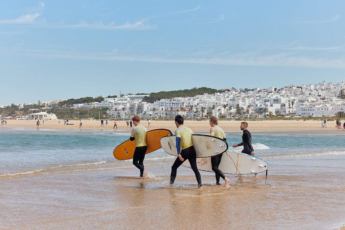 eine Gruppe von Surfern geht am Strand spazieren