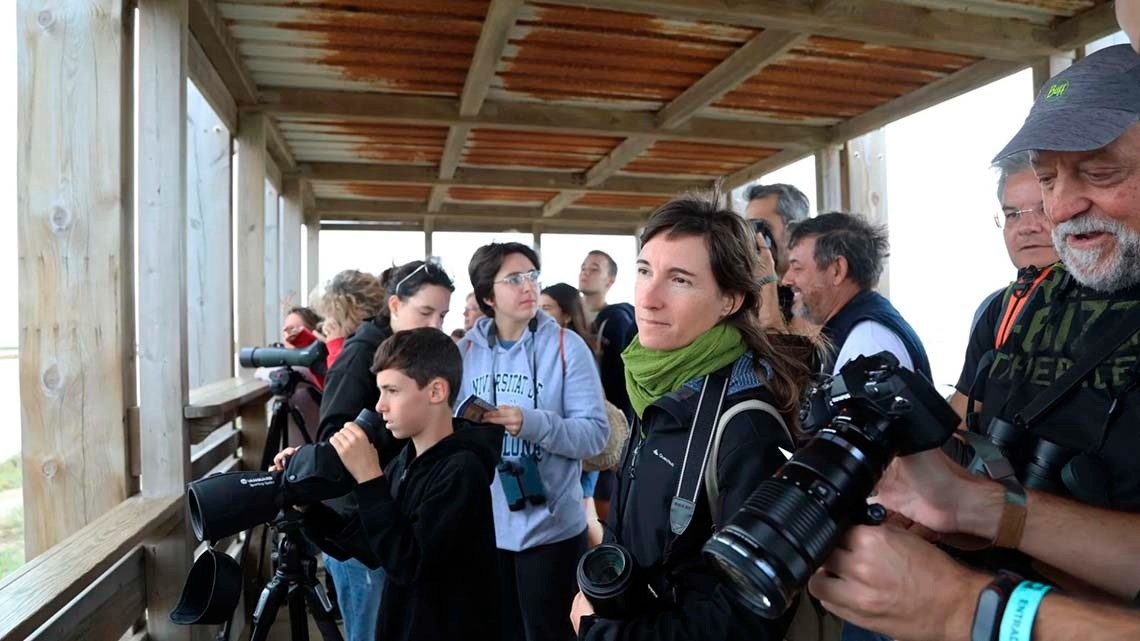 een groep mensen kijkt door een verrekijker terwijl een man een t-shirt draagt met het woord chief