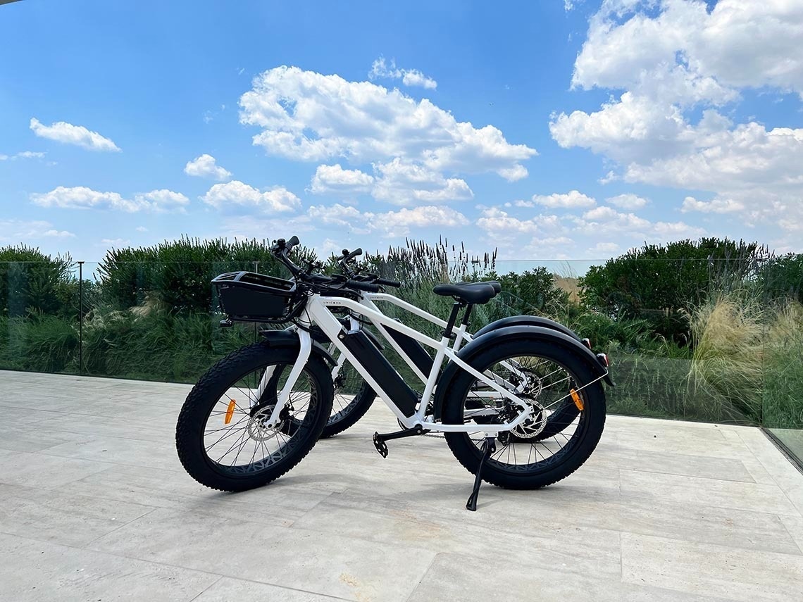 a white bicycle with a basket on the front is parked next to a black bicycle