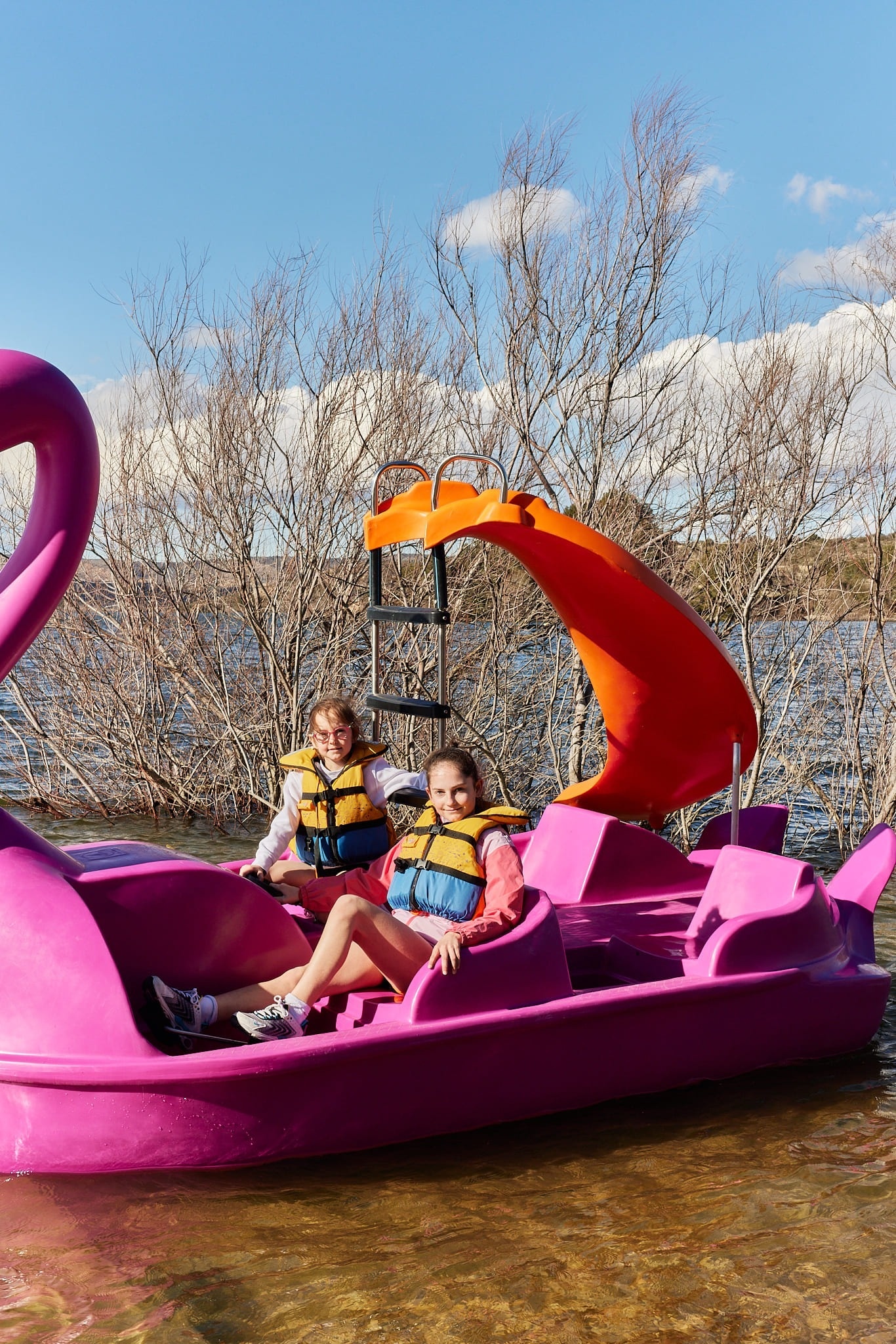 deux jeunes filles sont assises sur un bateau pédalo rose