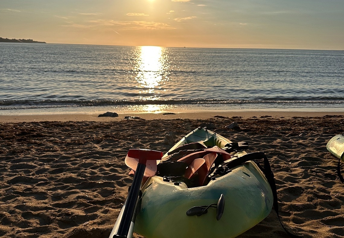 un kayak est posé sur la plage au coucher du soleil