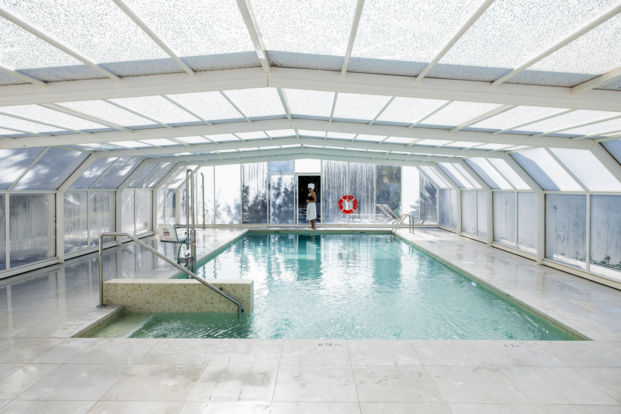 Piscina cubierta estilo Taiga: Corporativa con tumbonas, perfecta para relajarse.