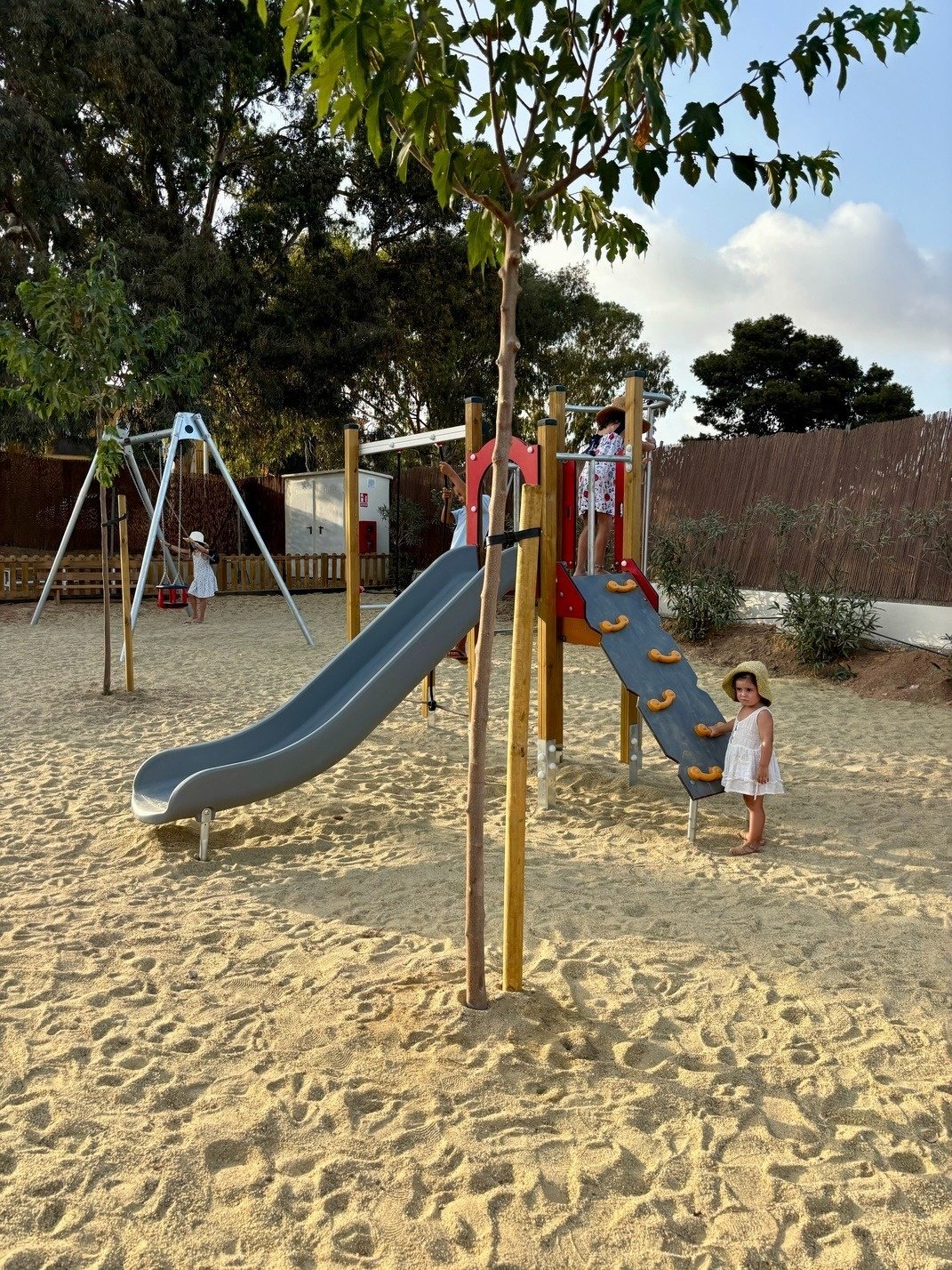 a little girl stands in front of a slide at a playground
