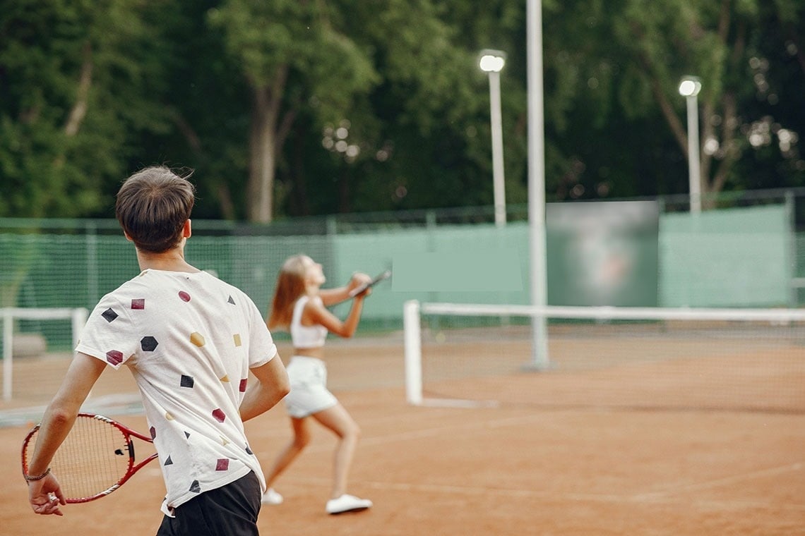 een man en een vrouw spelen tennis op een tennisbaan