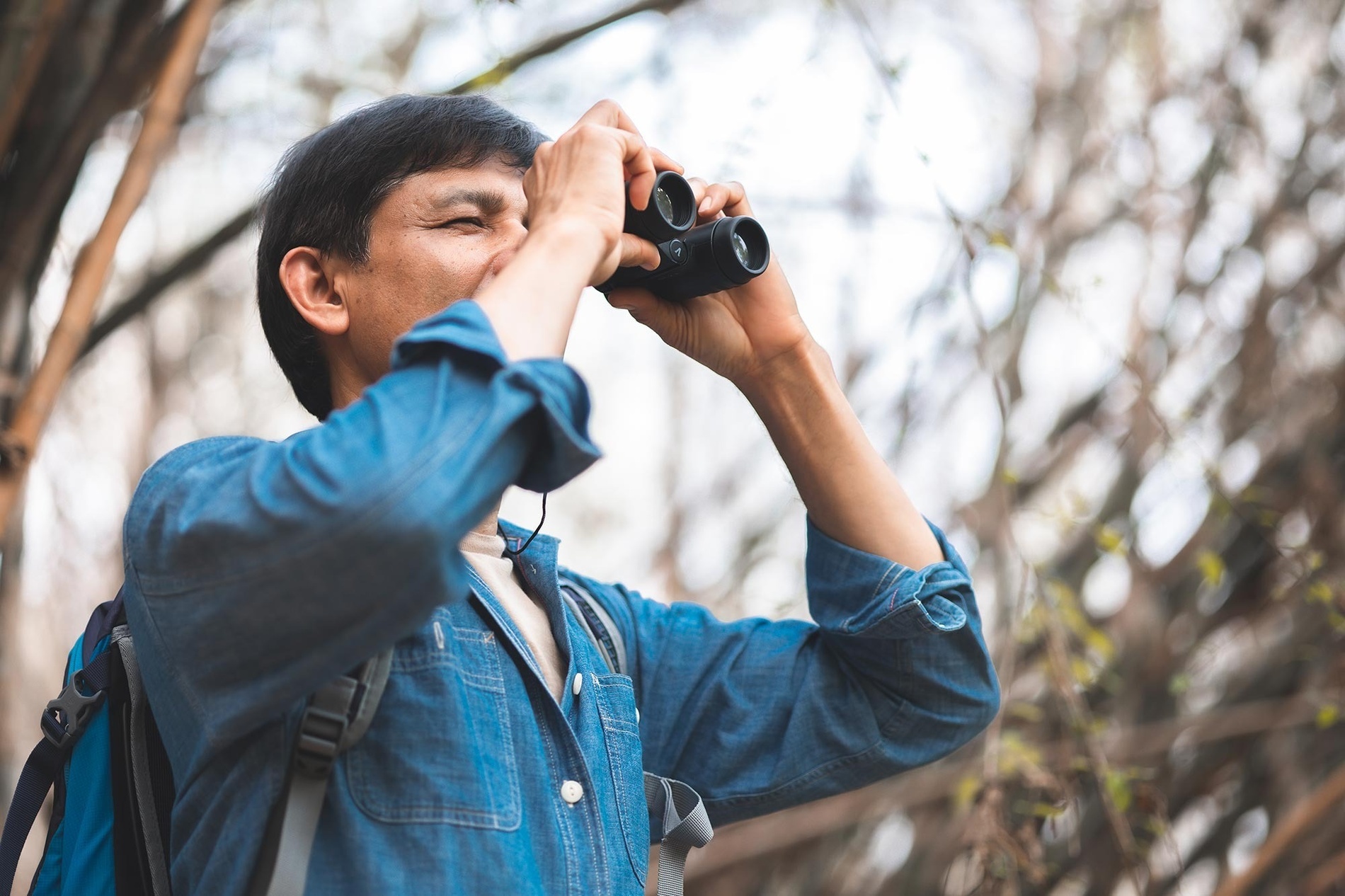 a man in a blue shirt is looking through binoculars
