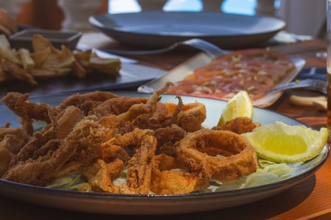 een bord gefrituurde inktvisringen met een schijfje citroen
