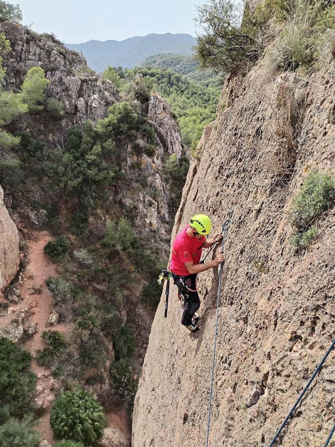a man in a red shirt is climbing a rock wall