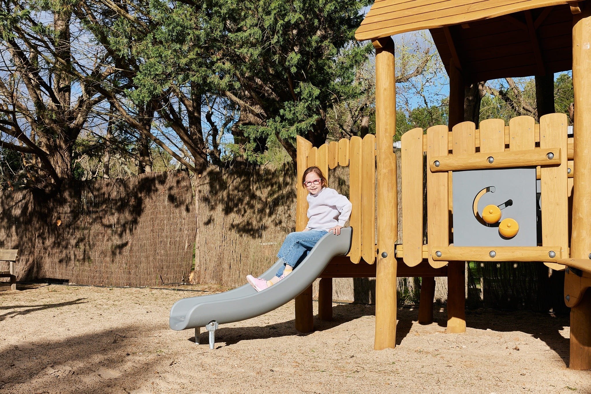 una niña se sienta en un tobogán en un patio de recreo