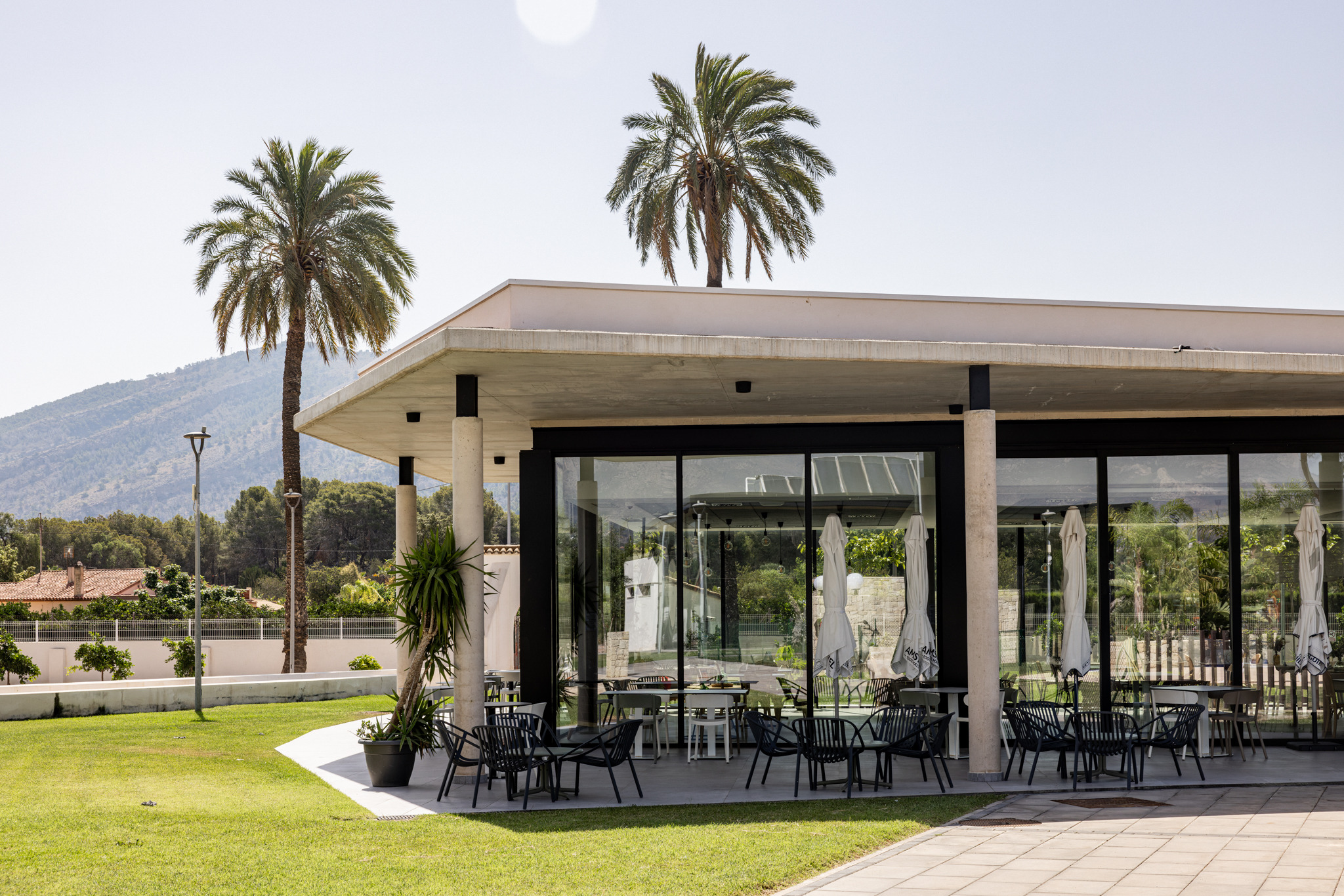 Exterior of a modern hotel restaurant with outdoor seating and palm trees Taiga: Corporativa