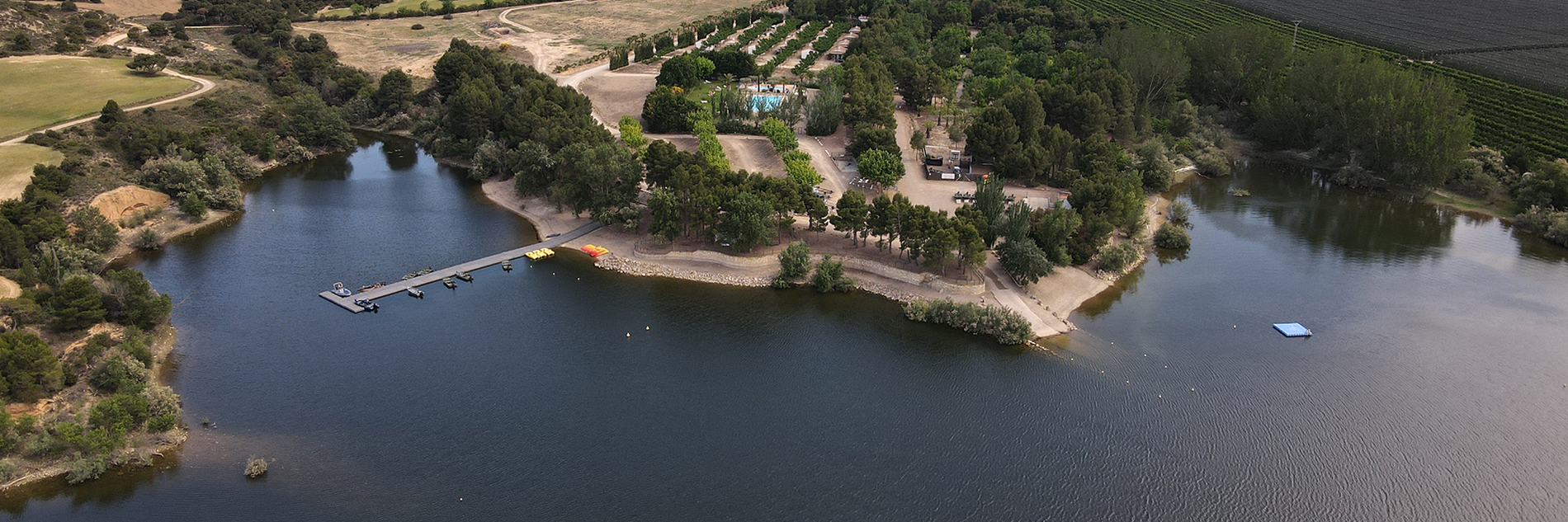 an aerial view of a lake with a dock in the middle