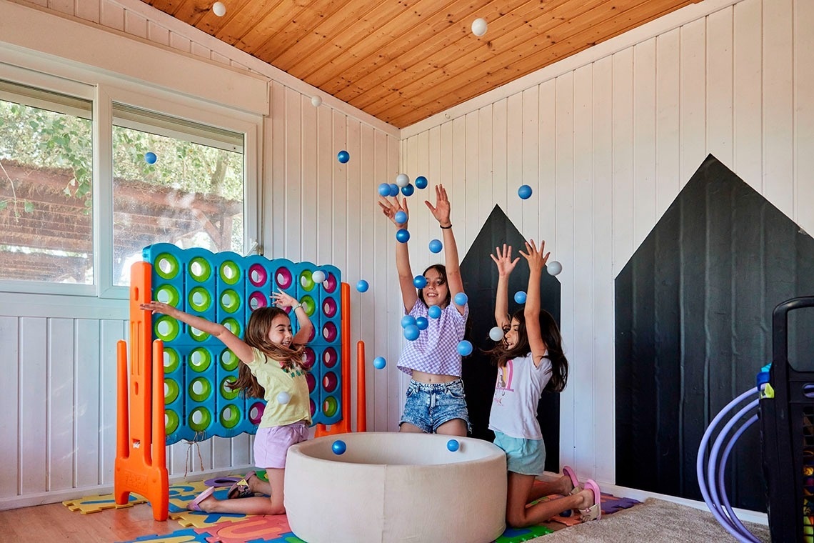 three girls are playing a game of connect four in a play room