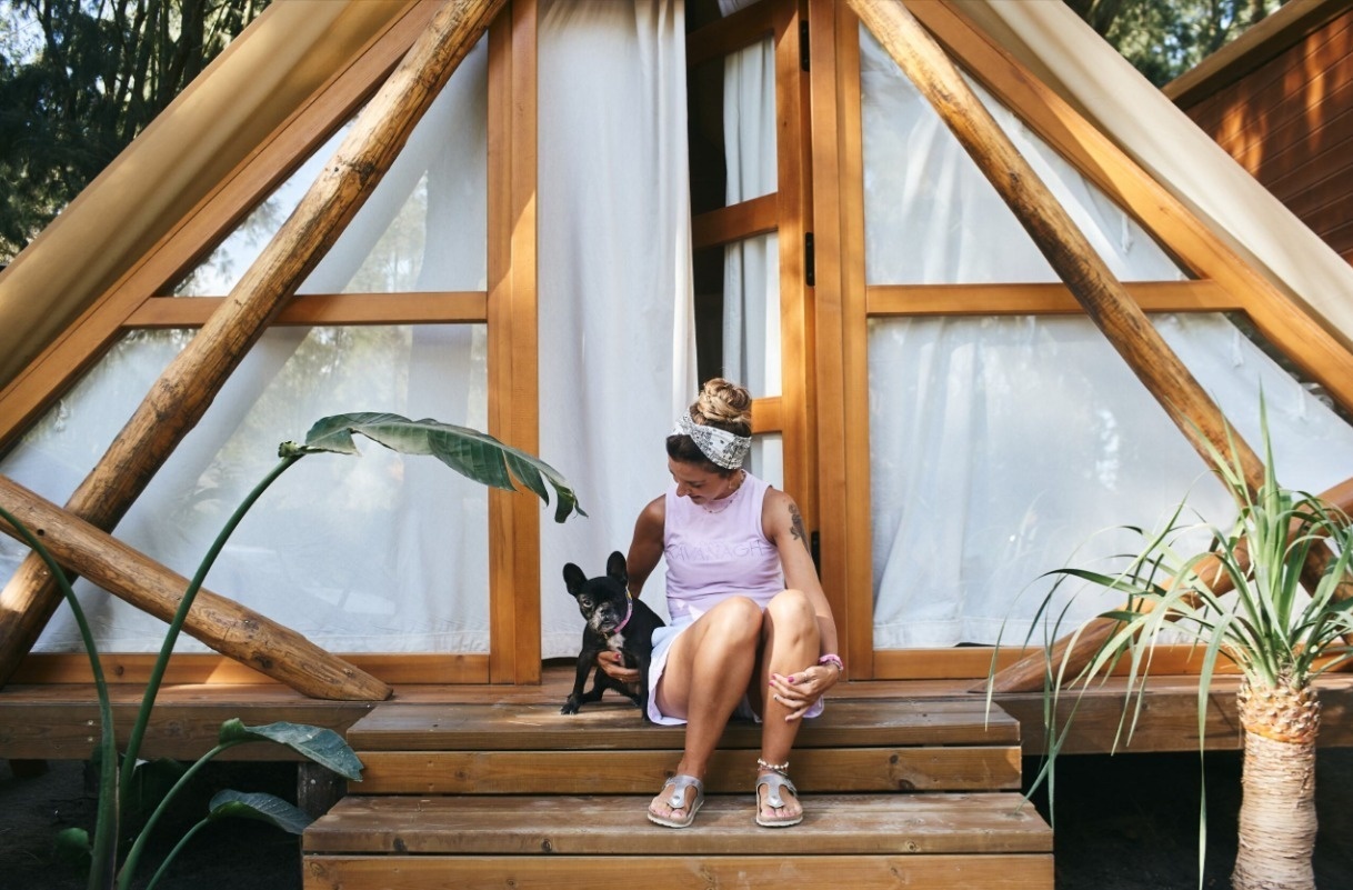 een vrouw zit met haar hond op de trappen van een houten hut