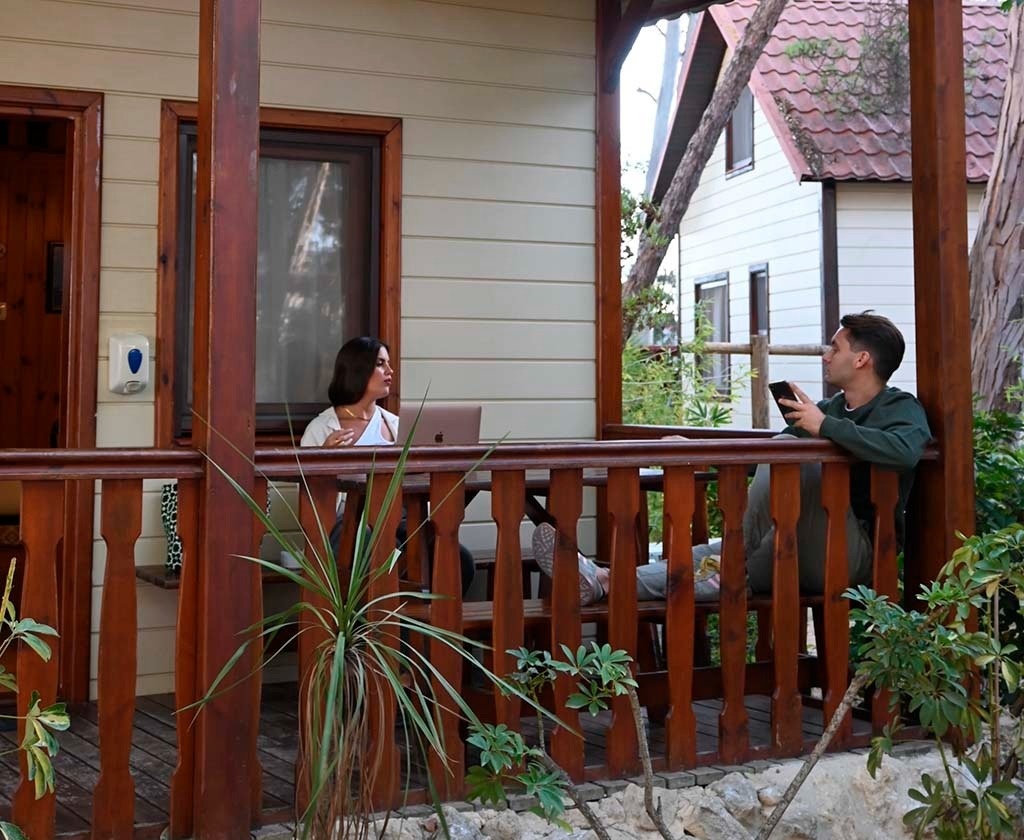 un homme et une femme sont assis sur un porche en bois avec un ordinateur portable