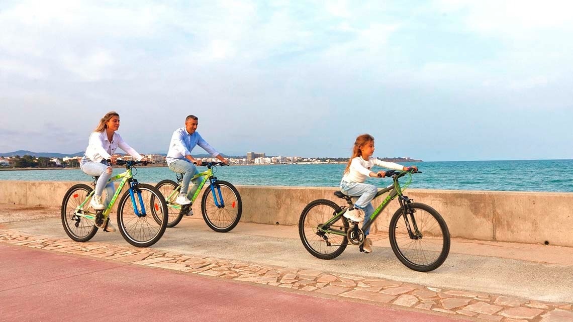 een man en twee vrouwen fietsen naast de oceaan