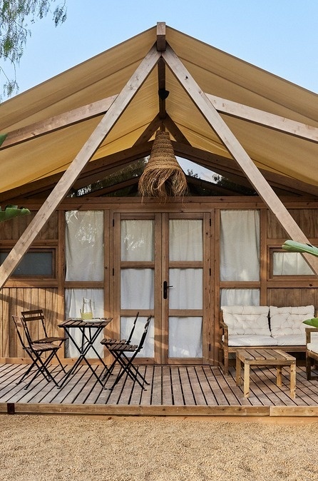 una casa de fusta coberta amb una tenda i un sofà i cadires