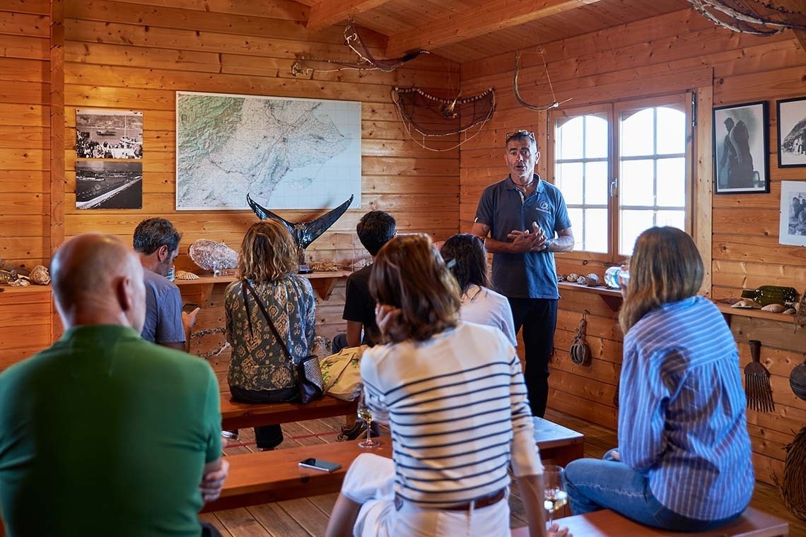een man houdt een toespraak voor een groep mensen in een houten kamer