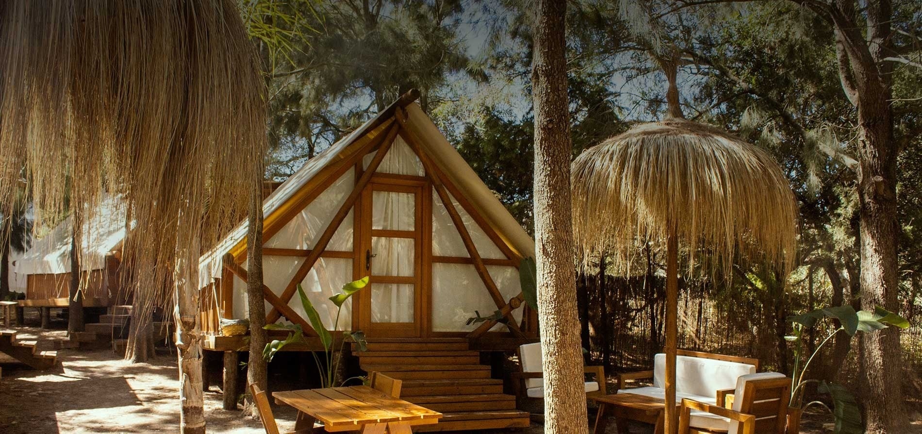 une cabane en bois entourée d' arbres avec une table et des chaises