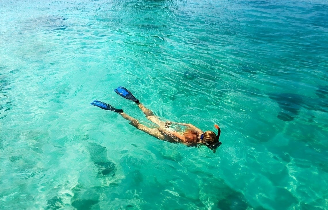 ein sandiger Strand mit einem Holzzaun im Vordergrund