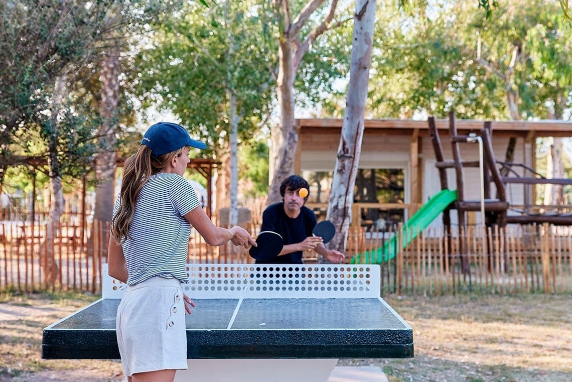 a man and a girl are playing ping pong outside