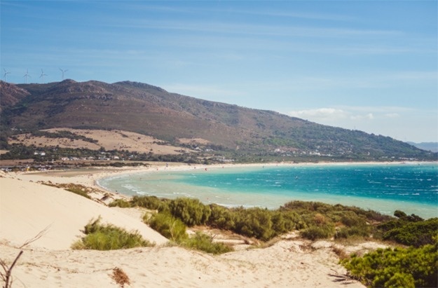 una playa con montañas en el fondo y un cielo azul