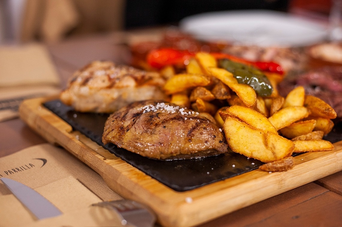 a steak and french fries on a wooden cutting board