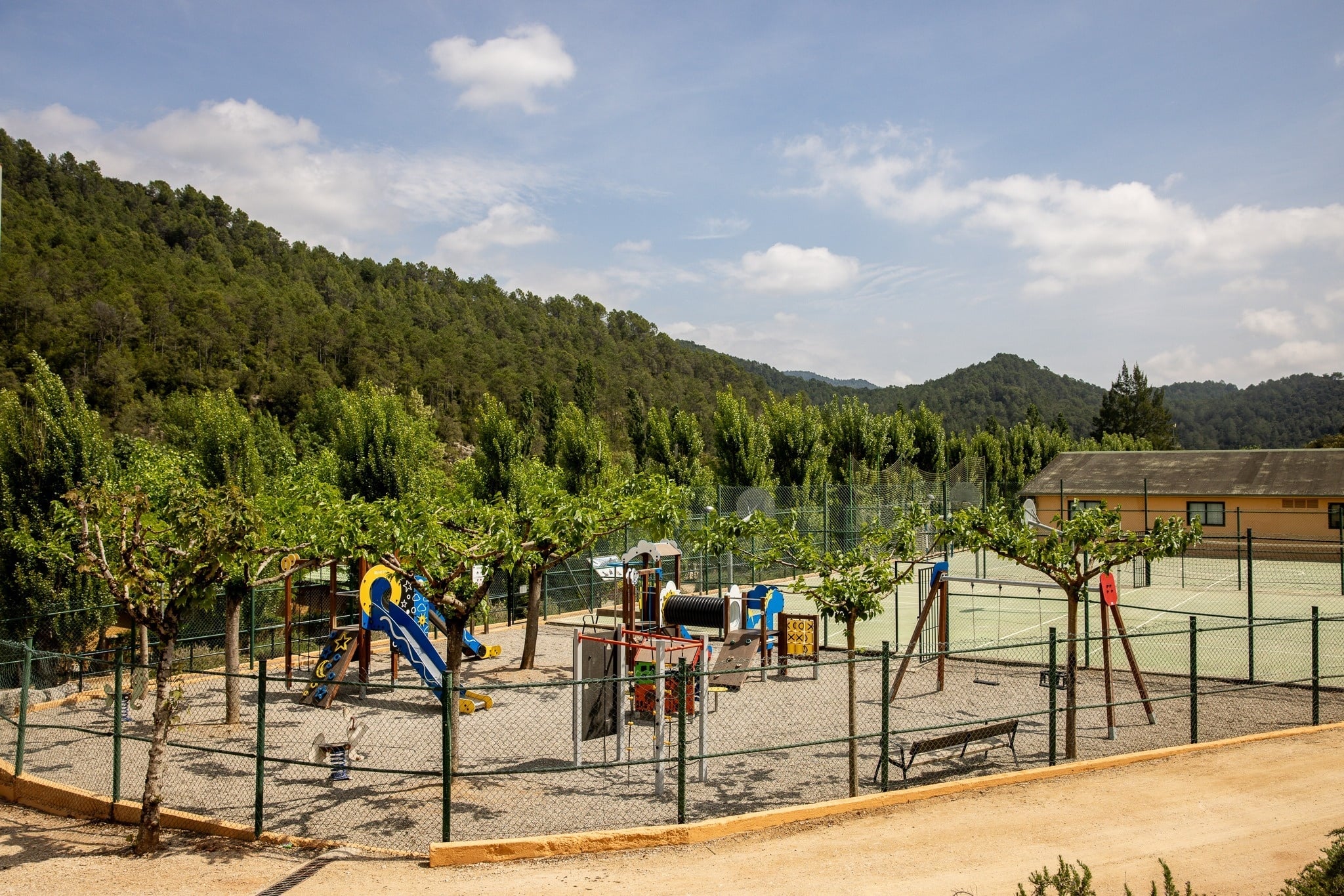 Taiga: Corporativa, parque infantil con tobogán azul y cancha de tenis exterior.