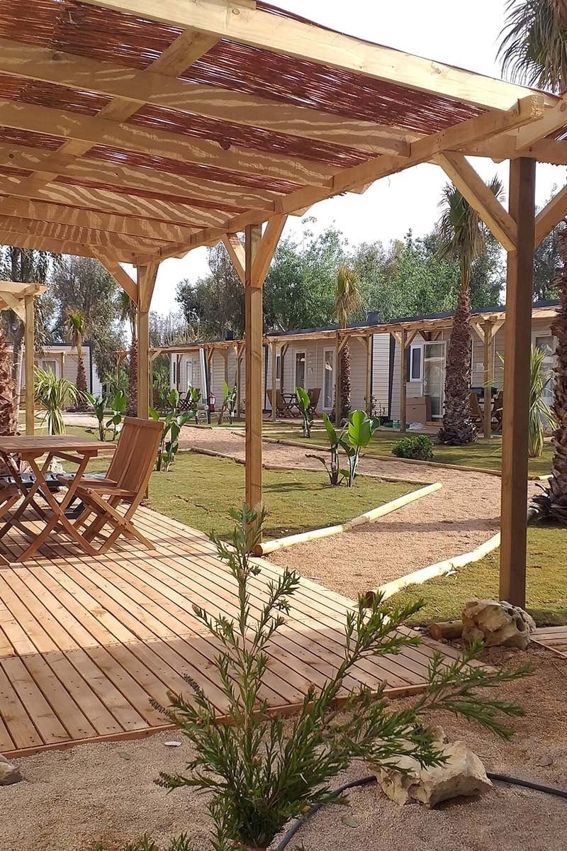 una terrassa de fusta amb una mesa i cadires sota un pergolat