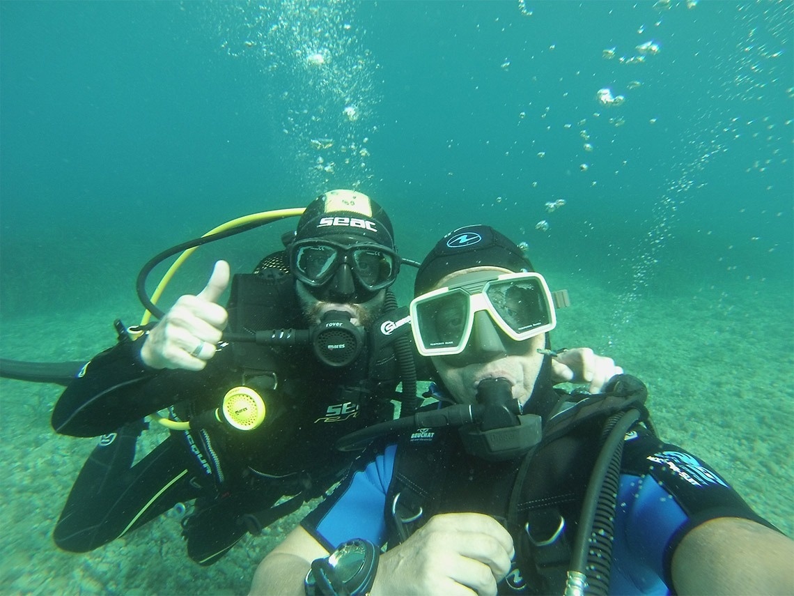 dos buzos dando un pulgar hacia arriba en el océano