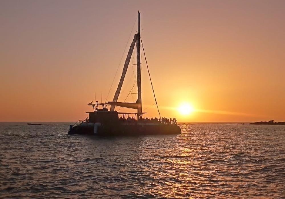 a sailboat is floating in the ocean at sunset