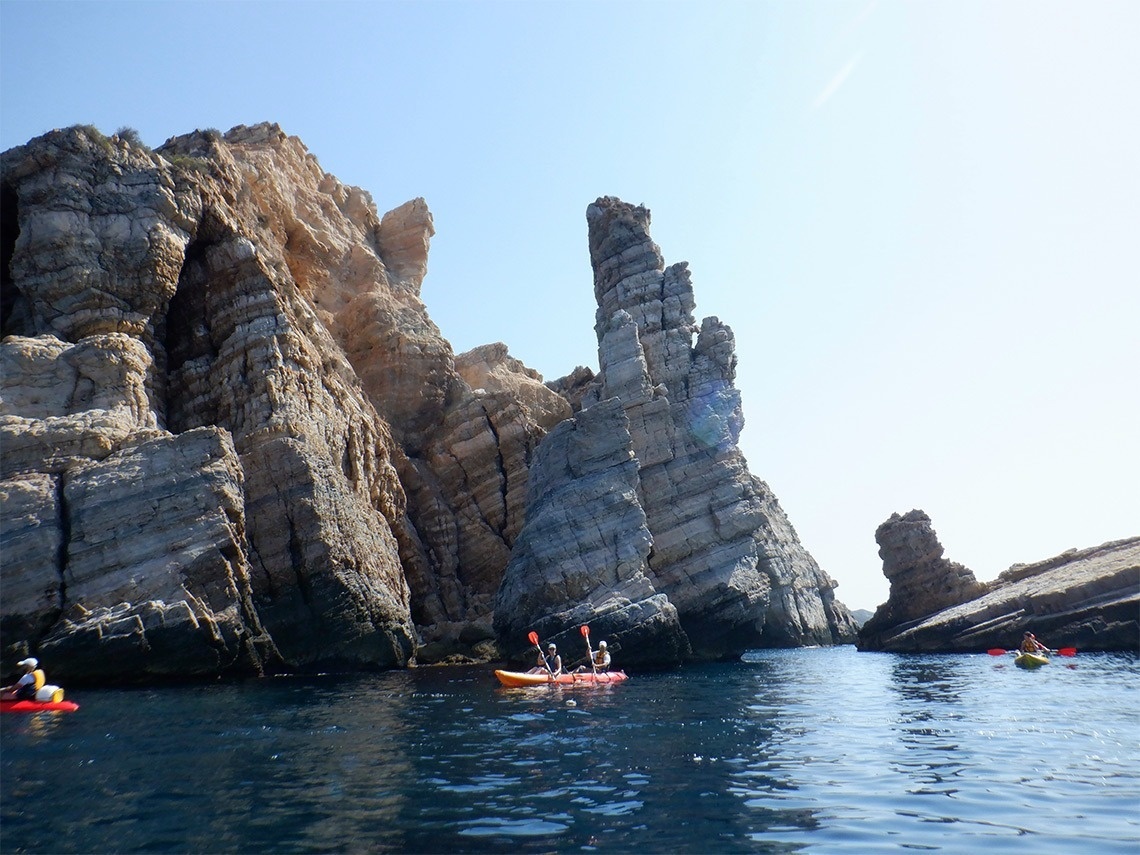 un grupo de personas en kayaks frente a una gran roca