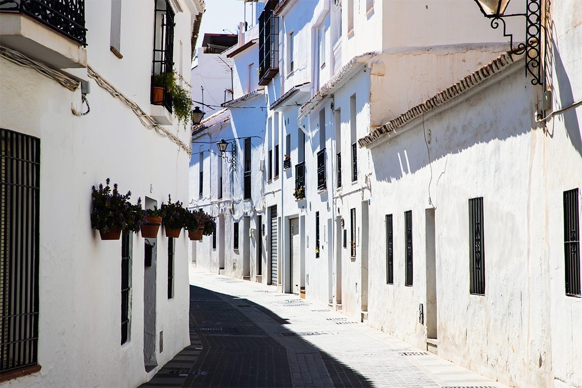 una calle estrecha llena de edificios blancos y macetas de flores