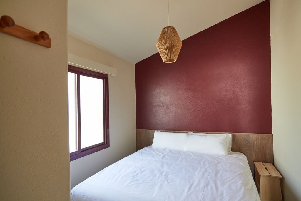 une chambre avec un lit blanc et un mur rouge