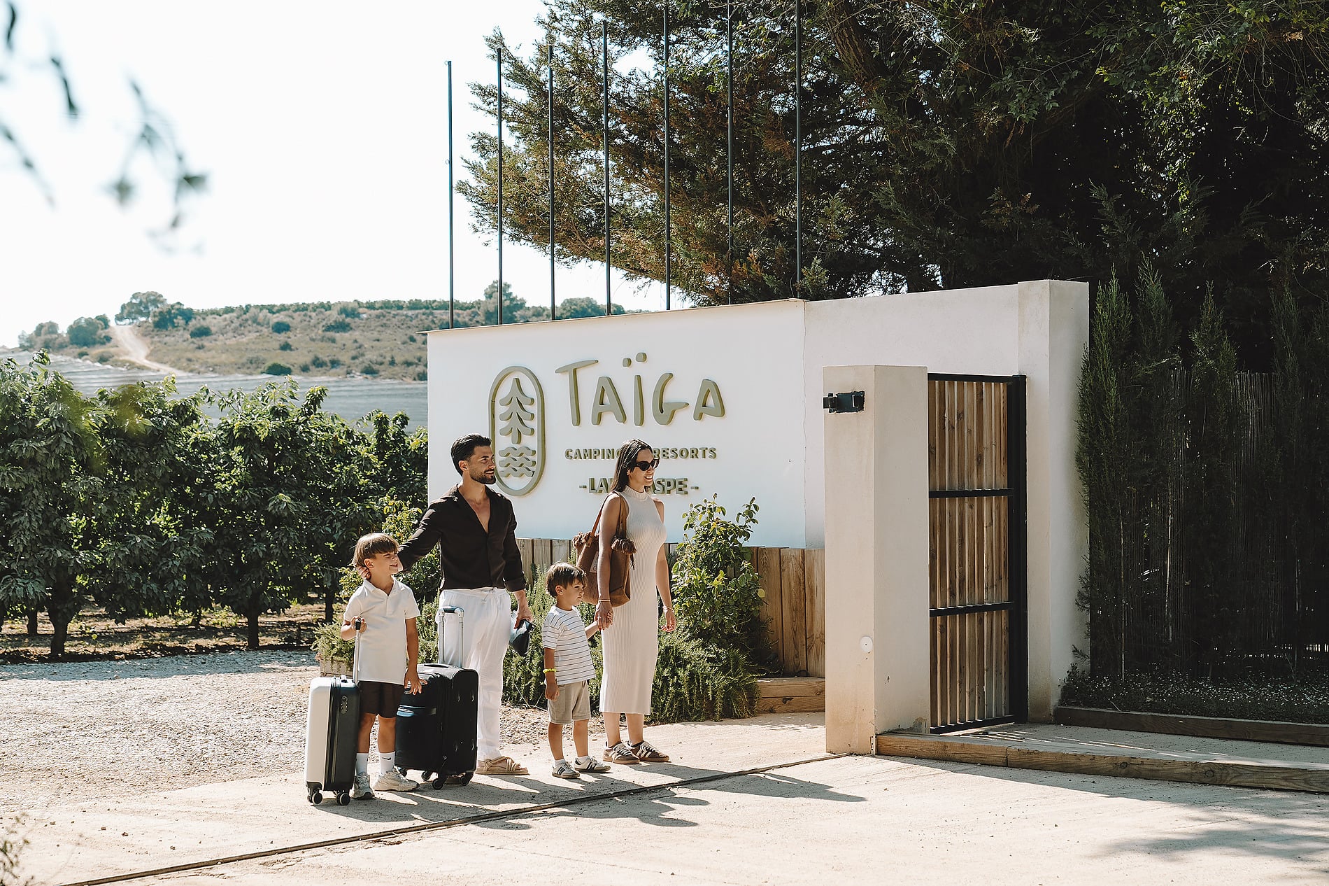 Familia llegando aTAIGA Lake Caspe | TAIGA | Campings & Resorts en España Taiga Camping Resorts con maletas.