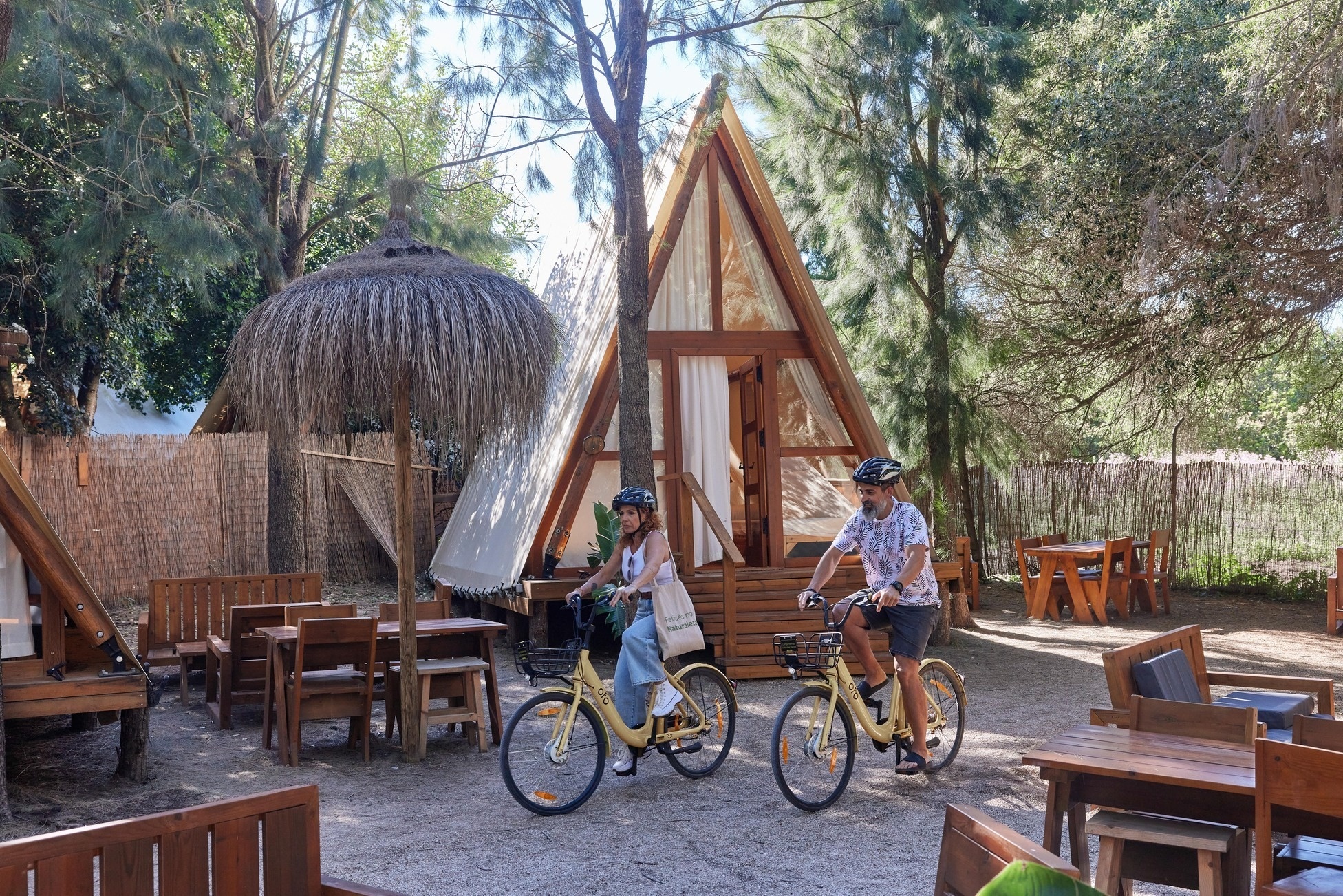 a man and a woman are riding bicycles in front of a wooden cabin