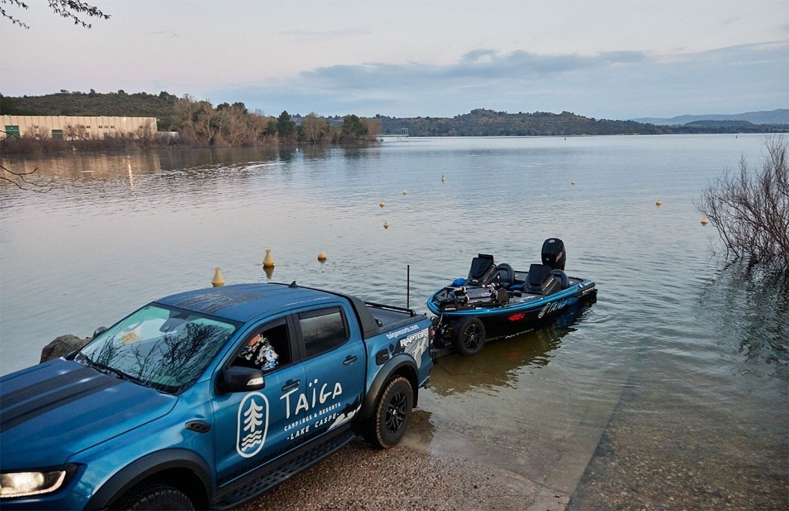 ein blauer taika-Truck steht neben einem Boot im Wasser