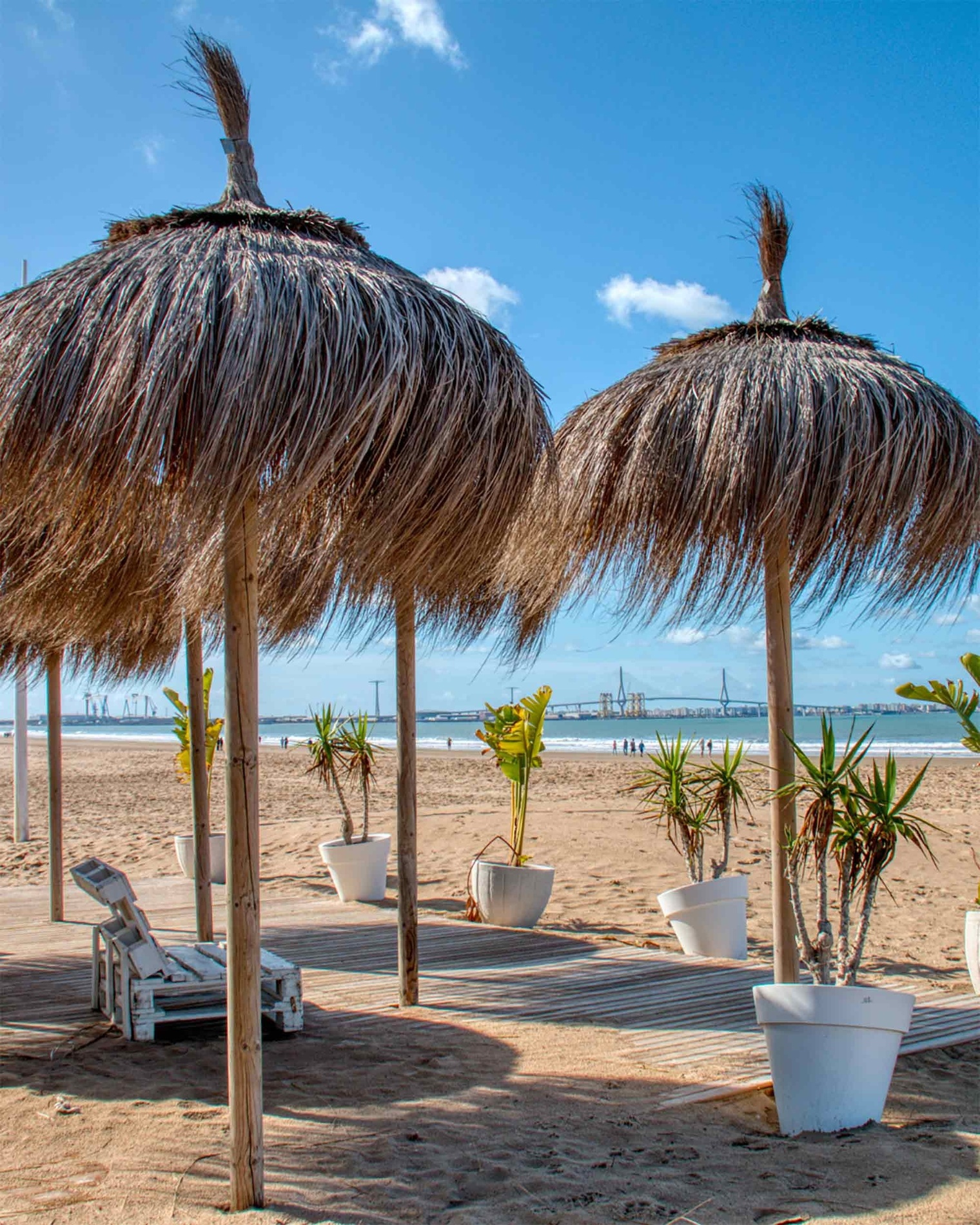ein Strand mit weißen Stühlen und Strohschirmen