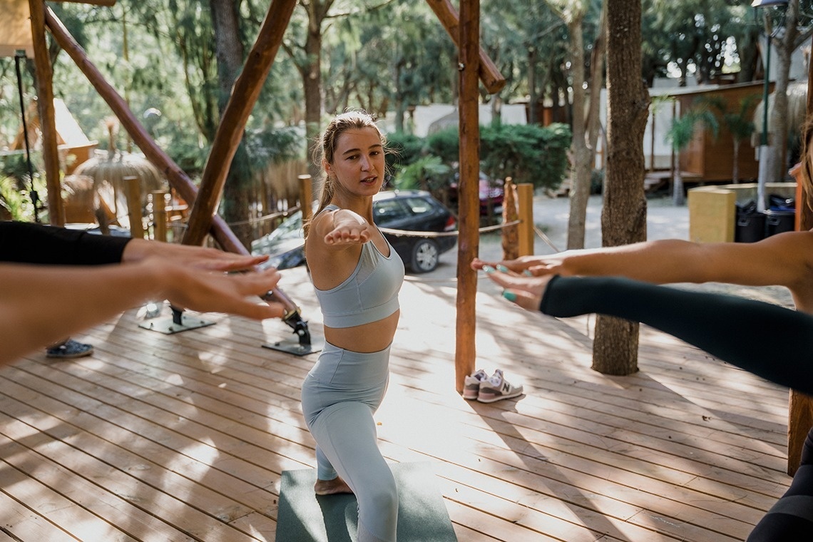 eine Gruppe von Menschen macht Yoga auf einem Holzdeck