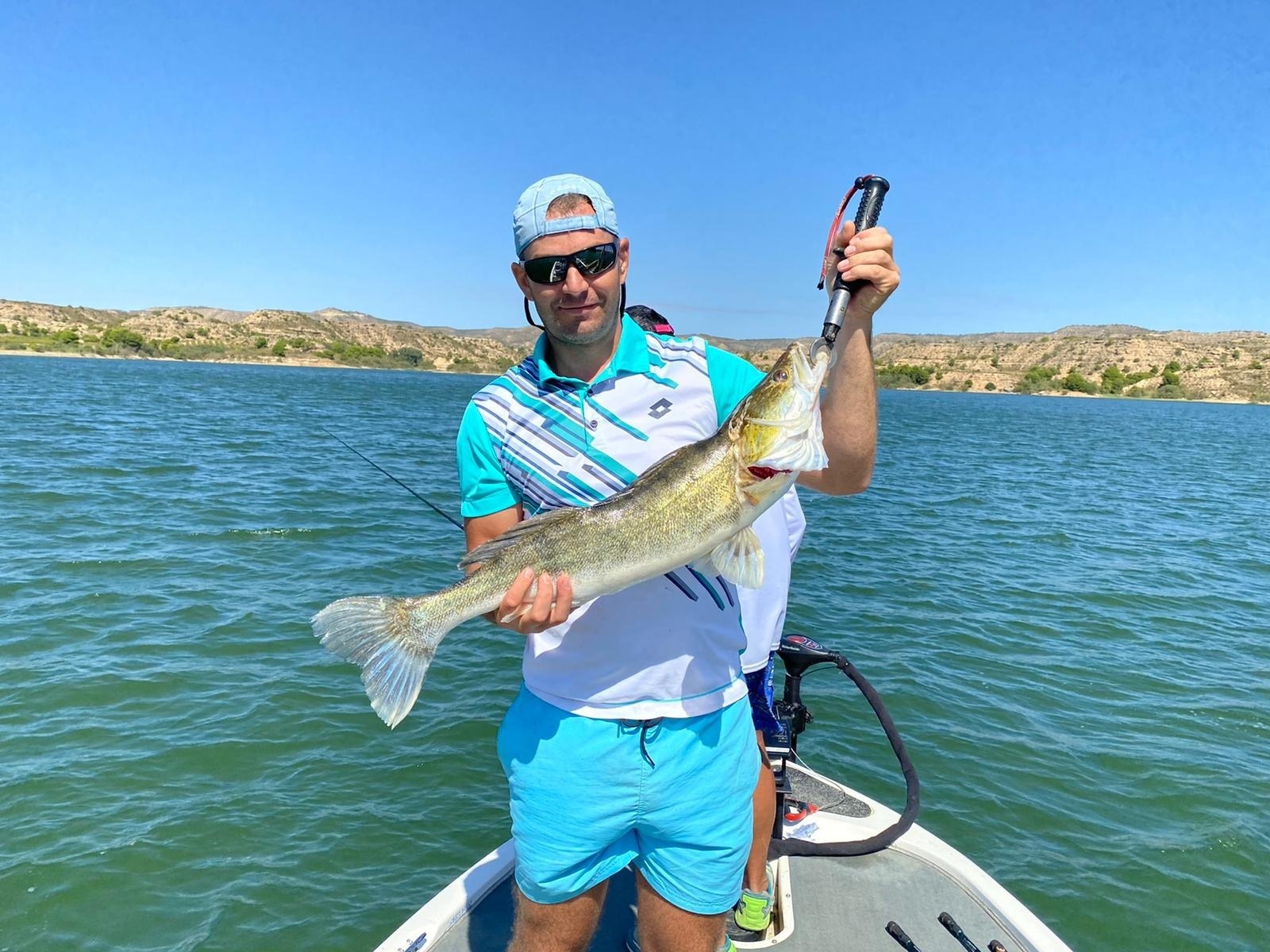 un hombre en un bote sostiene un pez grande en sus manos