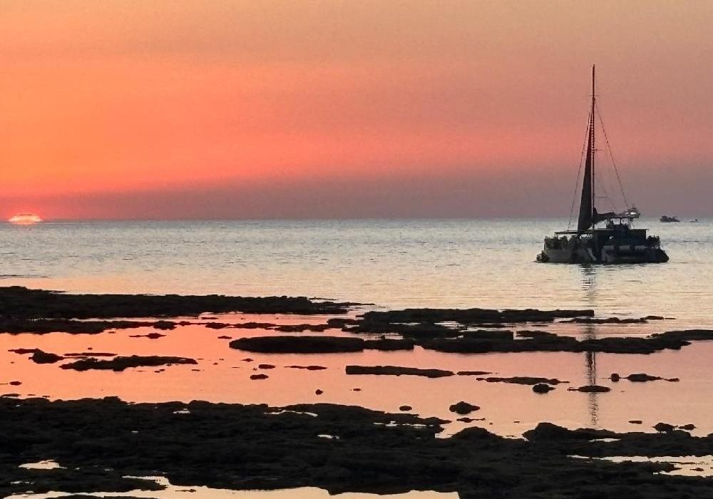 a boat in the ocean with a sunset in the background